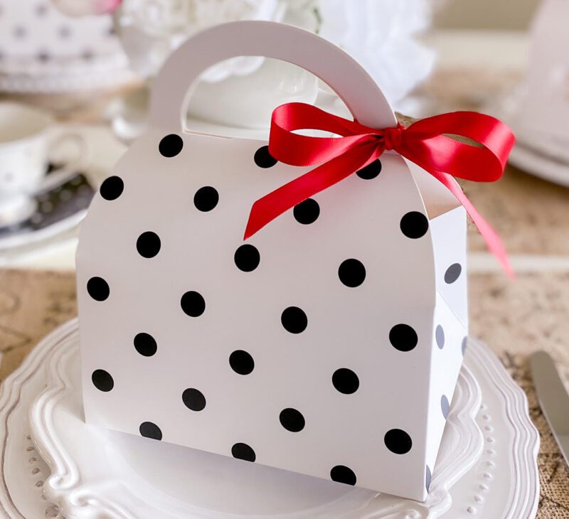 Cute purse shape cookie box in a black and white polka dot pattern. Tied with a red ribbon bow.