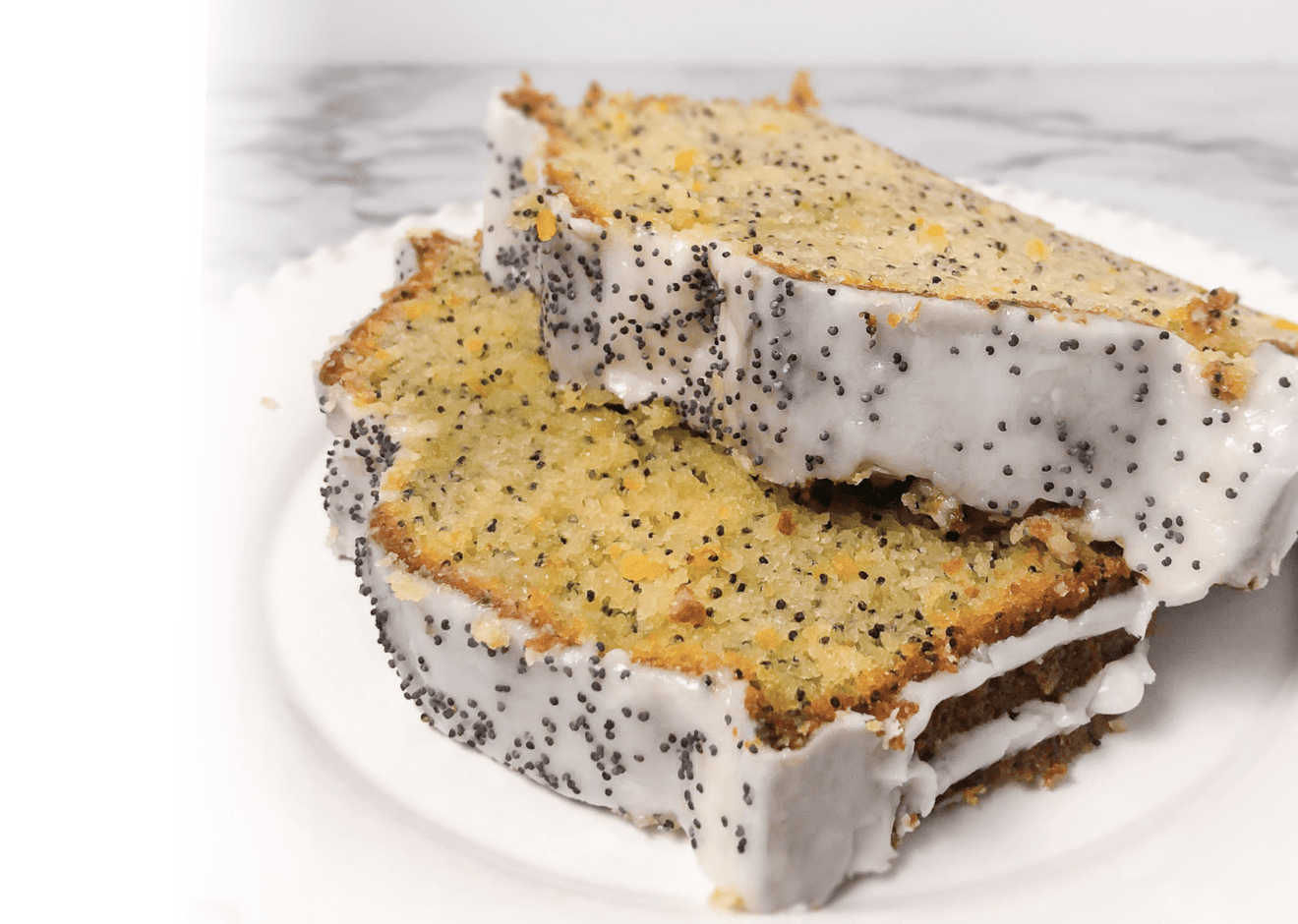 A white plate with 2 slices of lemon poppyseed cake with a crunchy sugary glazed sprinkled with more poppyseeds.