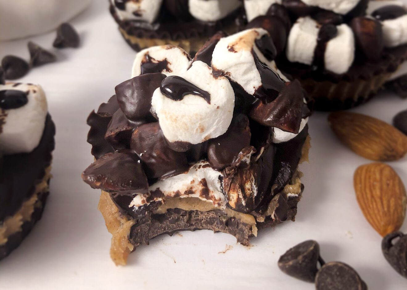 a plate full of rocky road treats with a bite taken out of one of them.