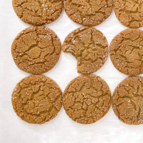 flat lay image of freshly baked gingersnaps. One has a bite taken out of it.