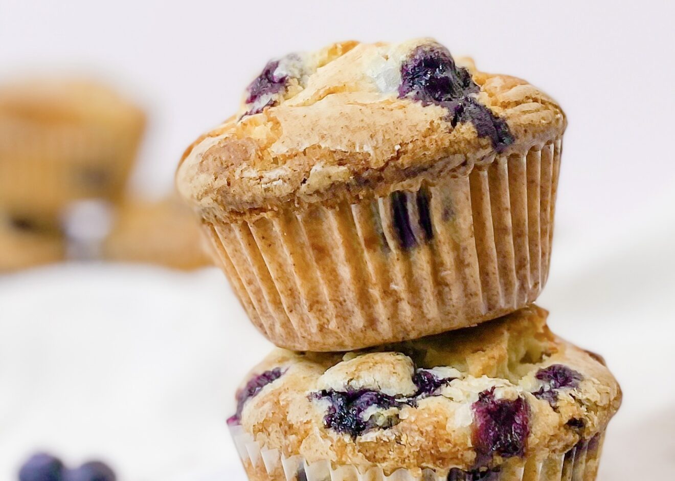 A stack of two bakery style blueberry muffins with crunchy glaze