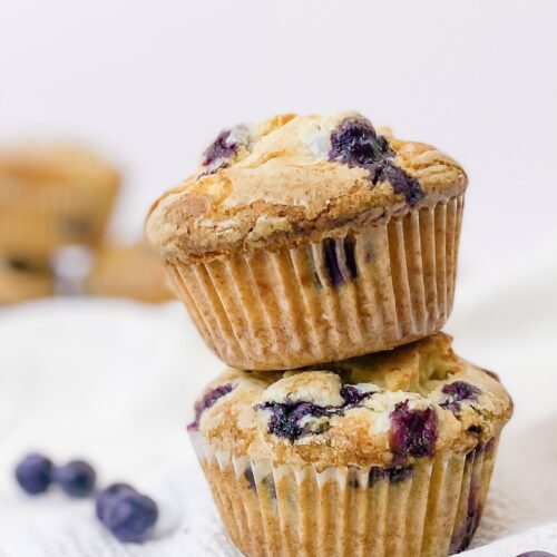 A stack of two bakery style blueberry muffins with crunchy glaze