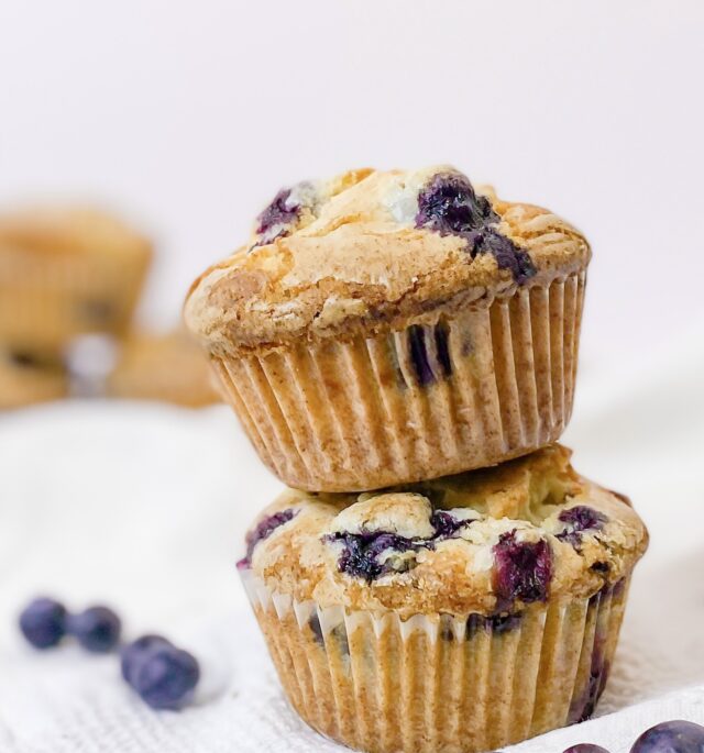 A stack of two bakery style blueberry muffins with crunchy glaze